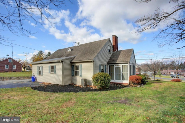 rear view of property featuring a yard, cooling unit, and a sunroom