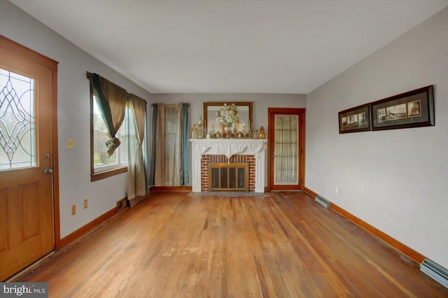 unfurnished living room featuring a fireplace, light hardwood / wood-style floors, and a healthy amount of sunlight