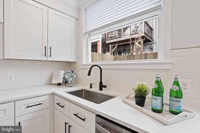 kitchen featuring backsplash, sink, white cabinets, and stainless steel dishwasher