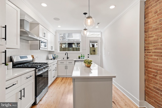 kitchen featuring gas stove, white cabinetry, brick wall, light hardwood / wood-style floors, and white microwave