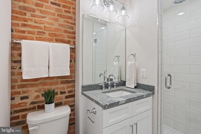 bathroom with vanity, brick wall, a shower with shower door, and toilet