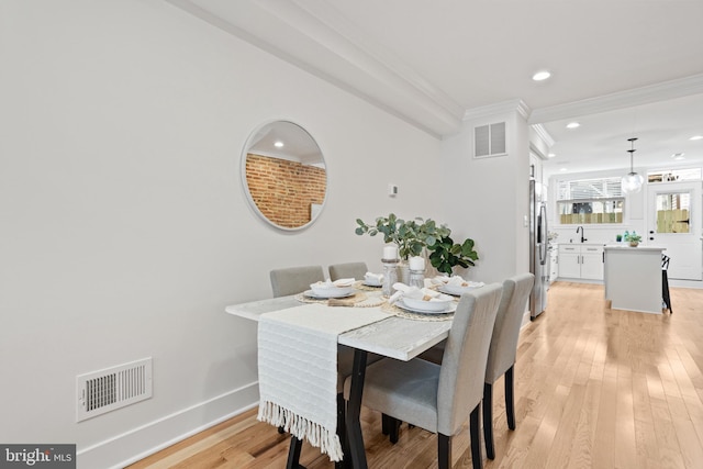 dining area featuring sink, crown molding, and light hardwood / wood-style flooring