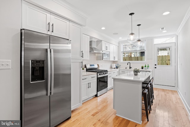 kitchen with a breakfast bar, light hardwood / wood-style flooring, a kitchen island, white cabinetry, and stainless steel appliances