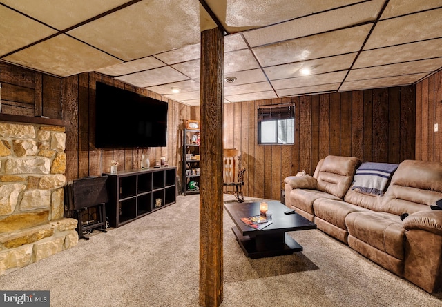 living room featuring carpet flooring, a drop ceiling, and wooden walls