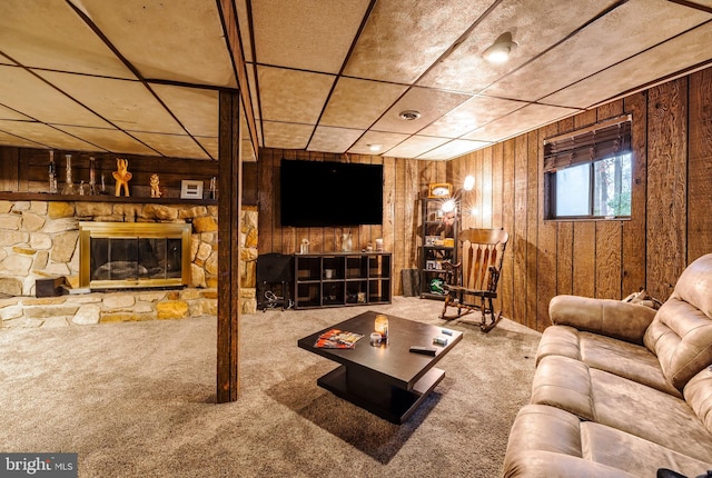 carpeted living room featuring a fireplace and wood walls