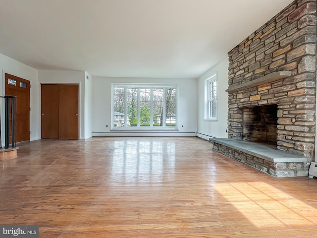 unfurnished living room featuring a fireplace, light hardwood / wood-style flooring, and a baseboard heating unit