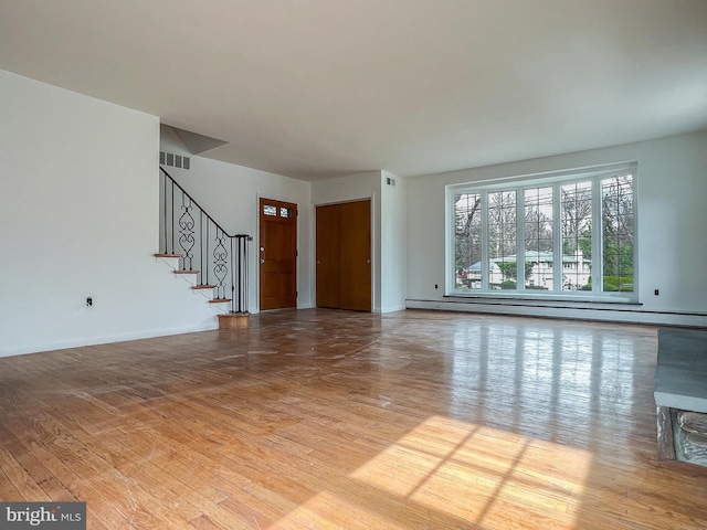 unfurnished living room with baseboard heating and light hardwood / wood-style flooring