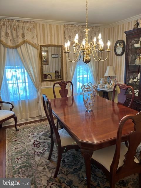 dining area featuring crown molding, wood-type flooring, and a notable chandelier