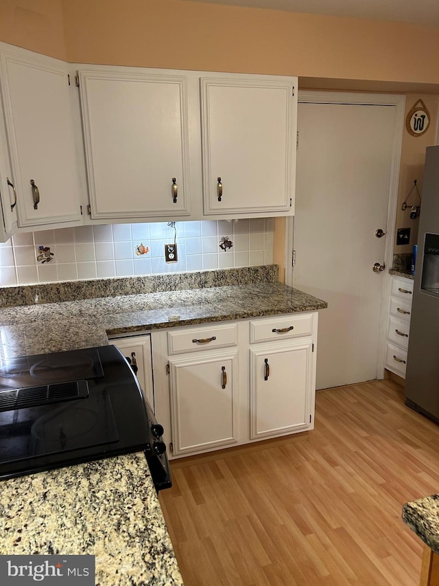 9221 Greenhouse Cir, Nottingham, MD 21236 - kitchen featuring light wood-style flooring, stainless steel refrigerator with ice dispenser, white cabinets, tasteful backsplash, and black range with electric cooktop