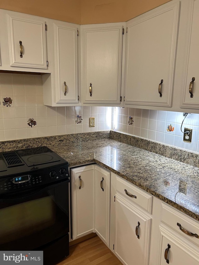 9221 Greenhouse Cir, Nottingham, MD 21236 - kitchen featuring black range with electric cooktop, white cabinetry, dark stone counters, decorative backsplash, and light wood finished floors