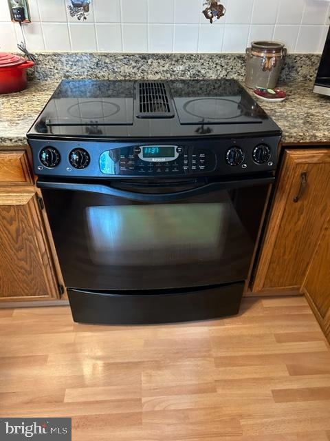 details featuring gas stove, dark stone countertops, and light hardwood / wood-style flooring