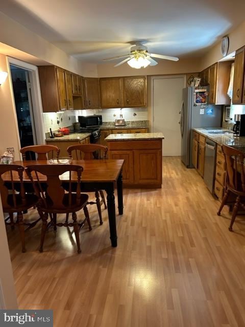 kitchen featuring sink, ceiling fan, decorative backsplash, light wood-type flooring, and stainless steel appliances