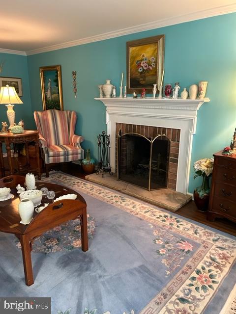 living area featuring a brick fireplace and ornamental molding