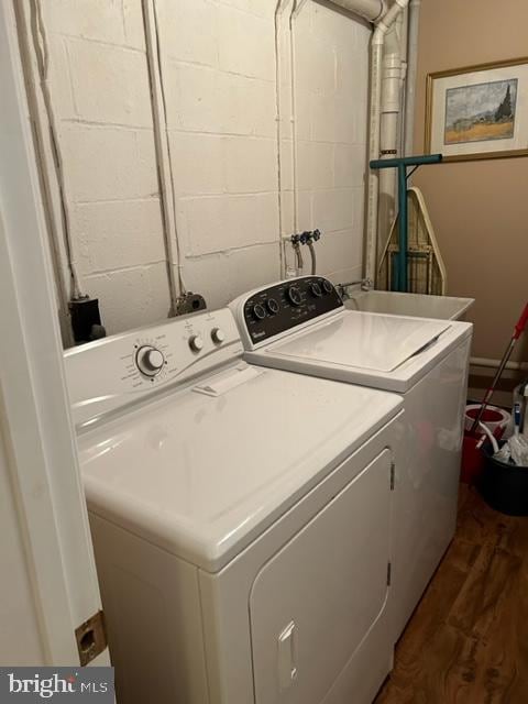 laundry room with dark wood-type flooring, washer and dryer, and sink