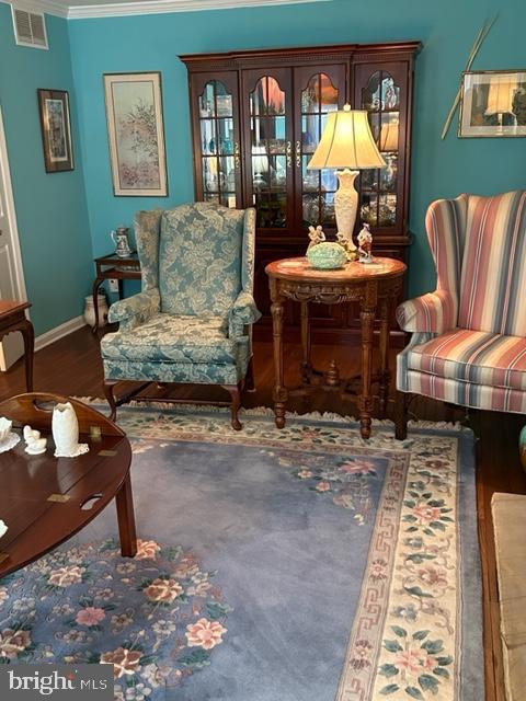 sitting room featuring wood-type flooring and ornamental molding