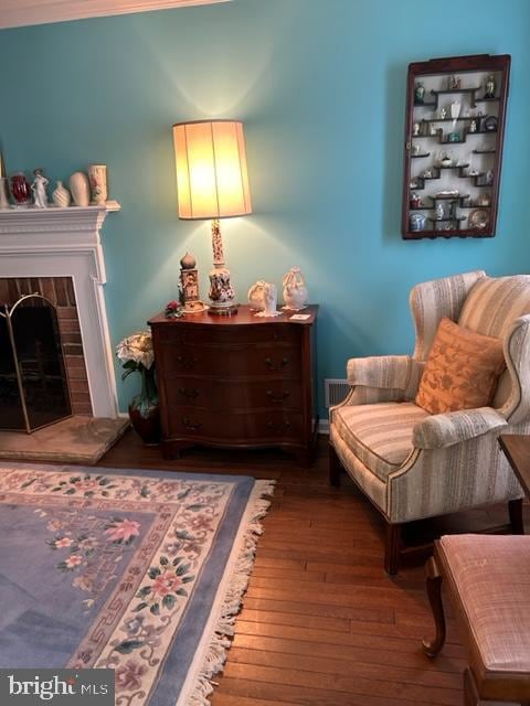 living area featuring a fireplace, hardwood / wood-style floors, and crown molding