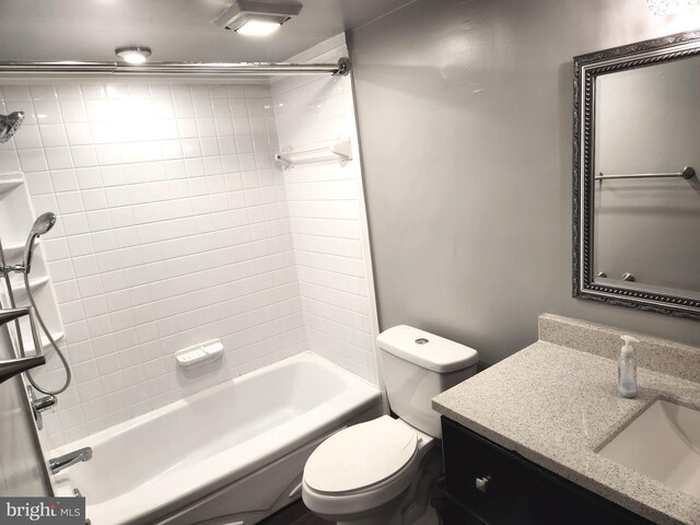 full bathroom featuring vanity, tiled shower / bath combo, and toilet