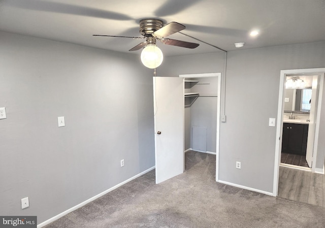 unfurnished bedroom featuring carpet floors, sink, a walk in closet, ceiling fan, and a closet