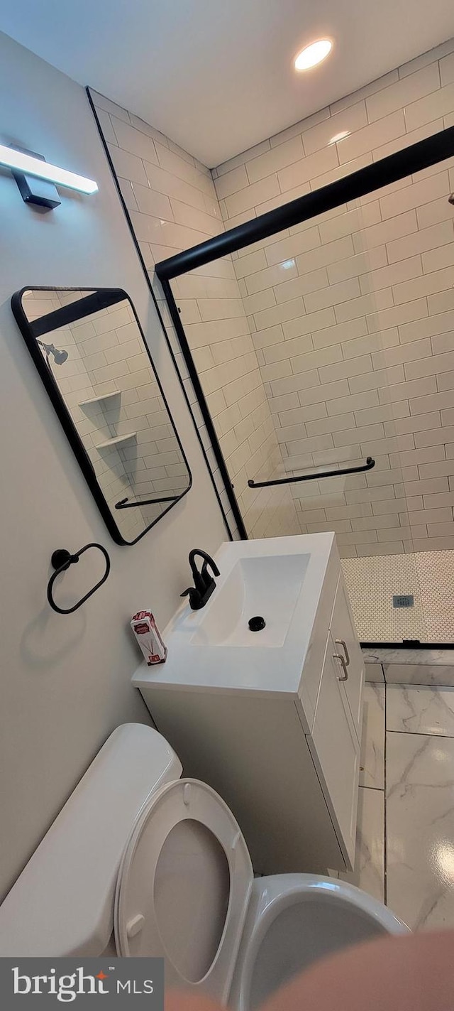 bathroom featuring toilet, an enclosed shower, and vanity