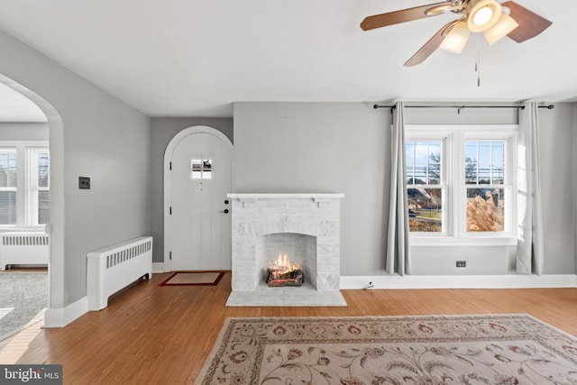 unfurnished living room with radiator, ceiling fan, and light wood-type flooring