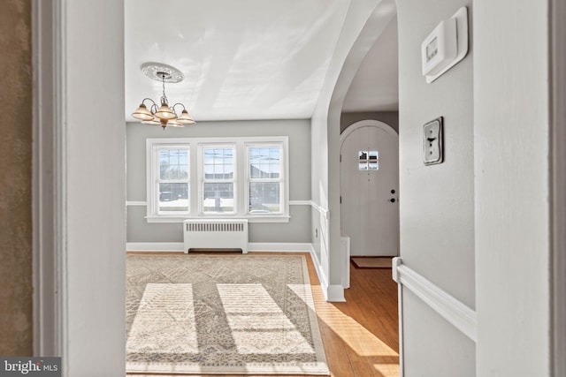 foyer entrance featuring radiator, a chandelier, and light hardwood / wood-style floors