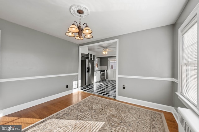 dining space with radiator, ceiling fan with notable chandelier, and hardwood / wood-style flooring