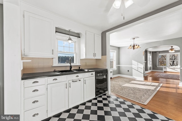 kitchen with dishwasher, ceiling fan with notable chandelier, sink, dark hardwood / wood-style floors, and white cabinetry