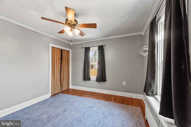 unfurnished bedroom featuring radiator, hardwood / wood-style flooring, ceiling fan, ornamental molding, and a closet