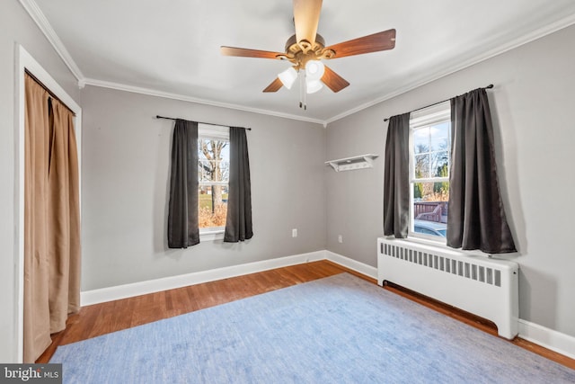 unfurnished bedroom with hardwood / wood-style floors, ceiling fan, radiator, and multiple windows