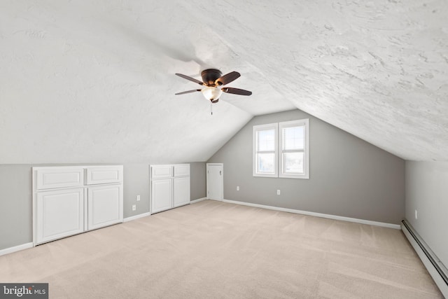 additional living space featuring a textured ceiling, lofted ceiling, light colored carpet, and a baseboard heating unit