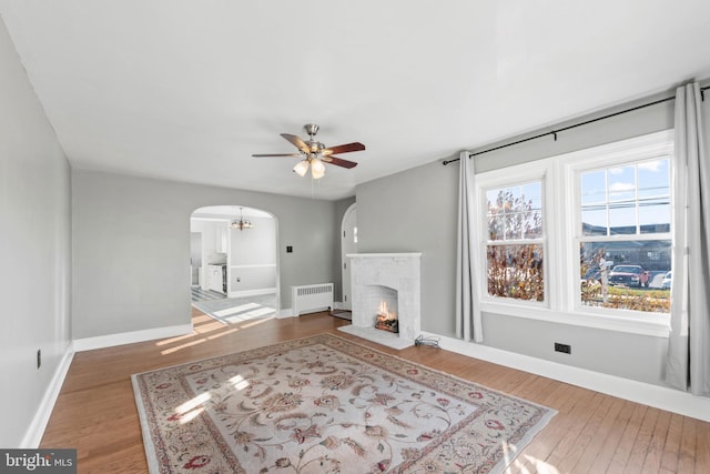 living room with a fireplace, ceiling fan, radiator heating unit, and hardwood / wood-style flooring