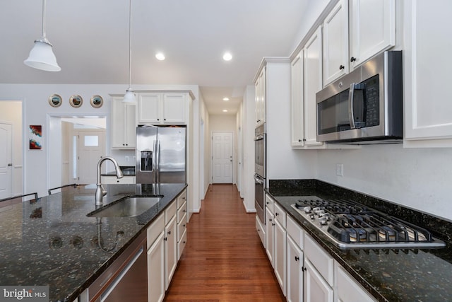 kitchen featuring sink, dark wood-type flooring, pendant lighting, white cabinets, and appliances with stainless steel finishes