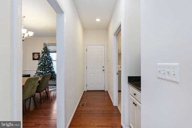 hallway with a notable chandelier and dark hardwood / wood-style floors