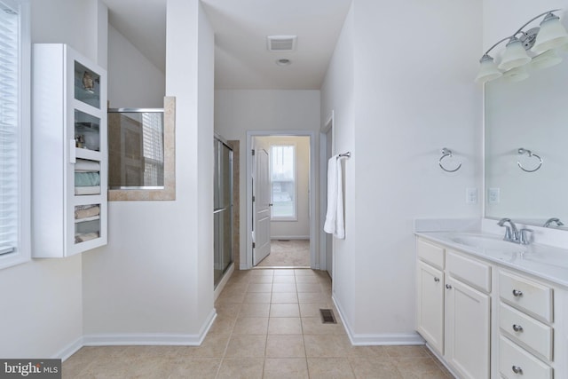 bathroom with tile patterned flooring, vanity, and walk in shower