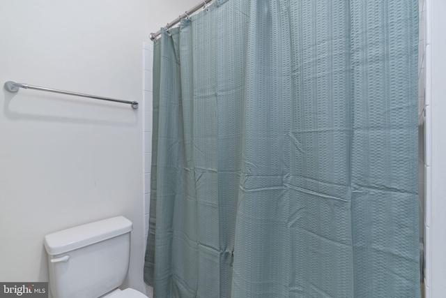 bathroom featuring a shower with curtain and toilet