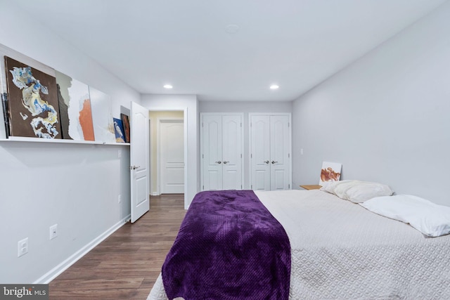 bedroom featuring dark hardwood / wood-style floors and multiple closets