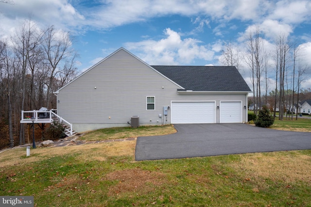 view of side of property with a yard, a garage, and central AC unit