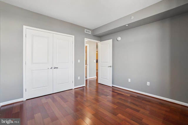 unfurnished bedroom with dark wood-type flooring and a closet