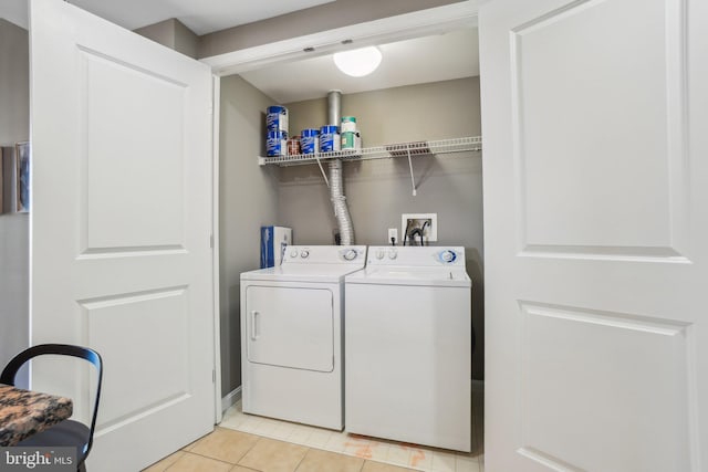 clothes washing area featuring light tile patterned floors and washer and clothes dryer