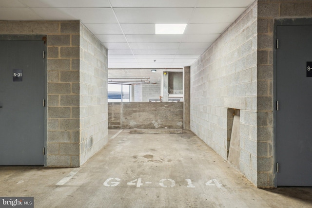 corridor featuring a drop ceiling, elevator, and concrete flooring