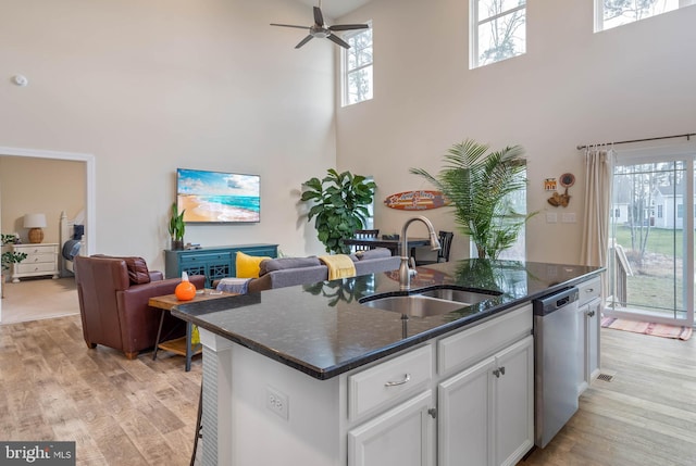 kitchen featuring dishwasher, a kitchen island with sink, a high ceiling, white cabinets, and sink