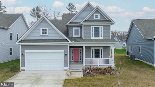 craftsman-style house featuring cooling unit, covered porch, a front yard, and a garage