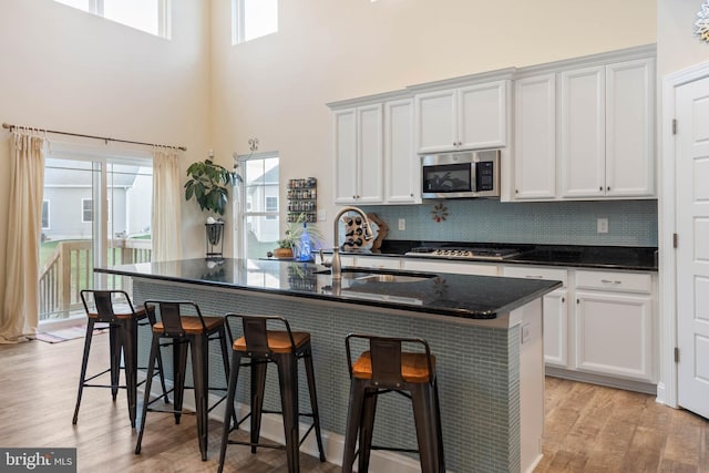 kitchen with plenty of natural light, an island with sink, appliances with stainless steel finishes, and light hardwood / wood-style flooring