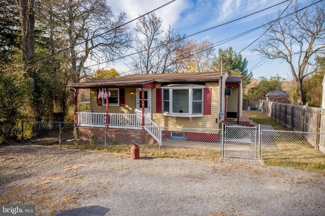 view of front of home with a fenced front yard, a porch, and a gate