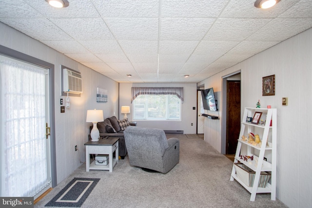 living room featuring a paneled ceiling, a wall mounted air conditioner, and carpet floors