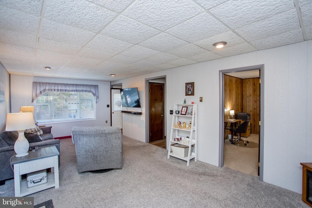 carpeted living area with a paneled ceiling