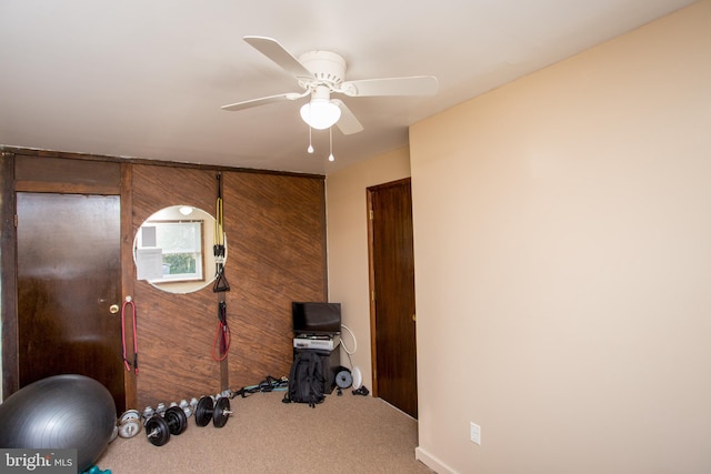 workout area featuring wood walls, carpet floors, and ceiling fan
