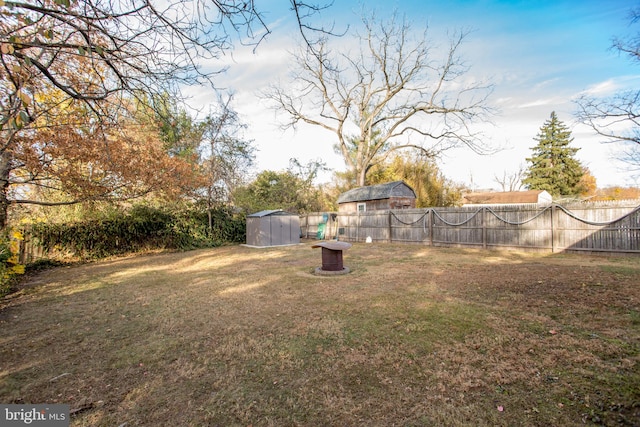 view of yard with an outdoor structure, a fenced backyard, and a shed