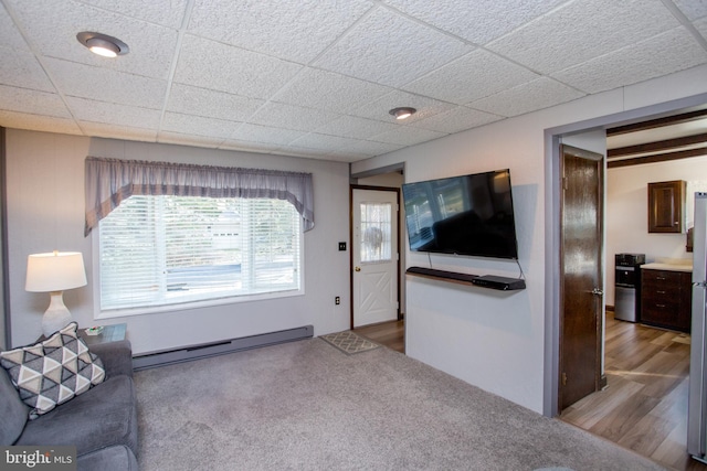 living area with a baseboard heating unit, wood finished floors, and a paneled ceiling