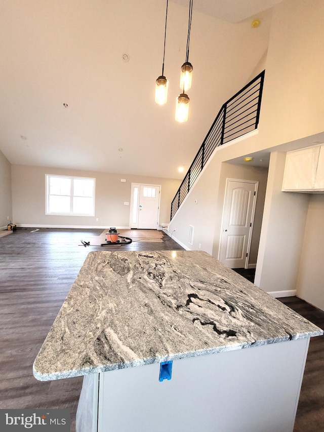 kitchen featuring a high ceiling, light stone counters, dark hardwood / wood-style flooring, and decorative light fixtures